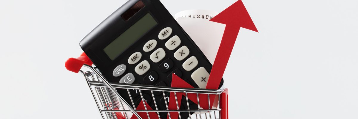 Miniature Shopping cart trolley, calculator, shopping receipt and red arrow up on white background with copy space. Concept for grocery expenses and consumerism